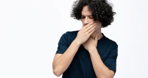 a photo of a man showing why bad breath is so bad while holding hands in front of his mouth