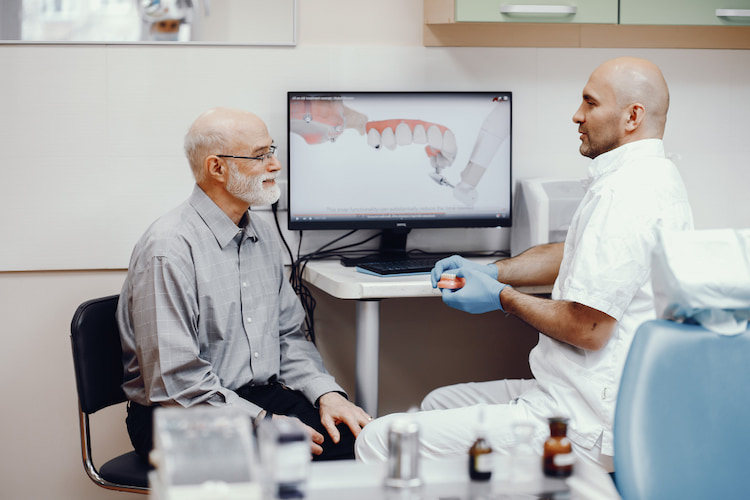a dentist explaining common reasons denture sore develop to an adult patient  