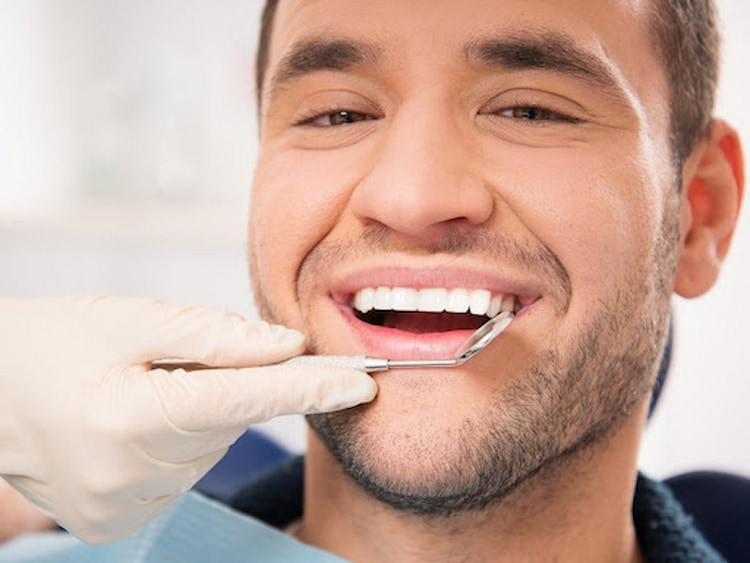 a photo of a man with dental veneers and a dentist checking for the complications of veneers 