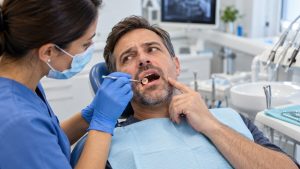Dentist examining a tooth after a dental filling has fallen out.