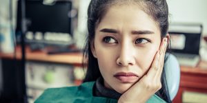 Woman holding her jaw with a toothache at home on a Saturday