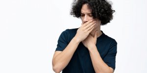 a photo of a man showing why bad breath is so bad while holding hands in front of his mouth